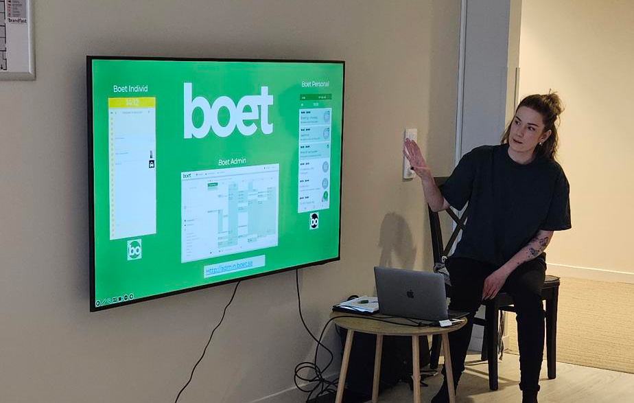Kvinna sitter och pekar på en tv-skärm som visar LSS-verktyget Boet.